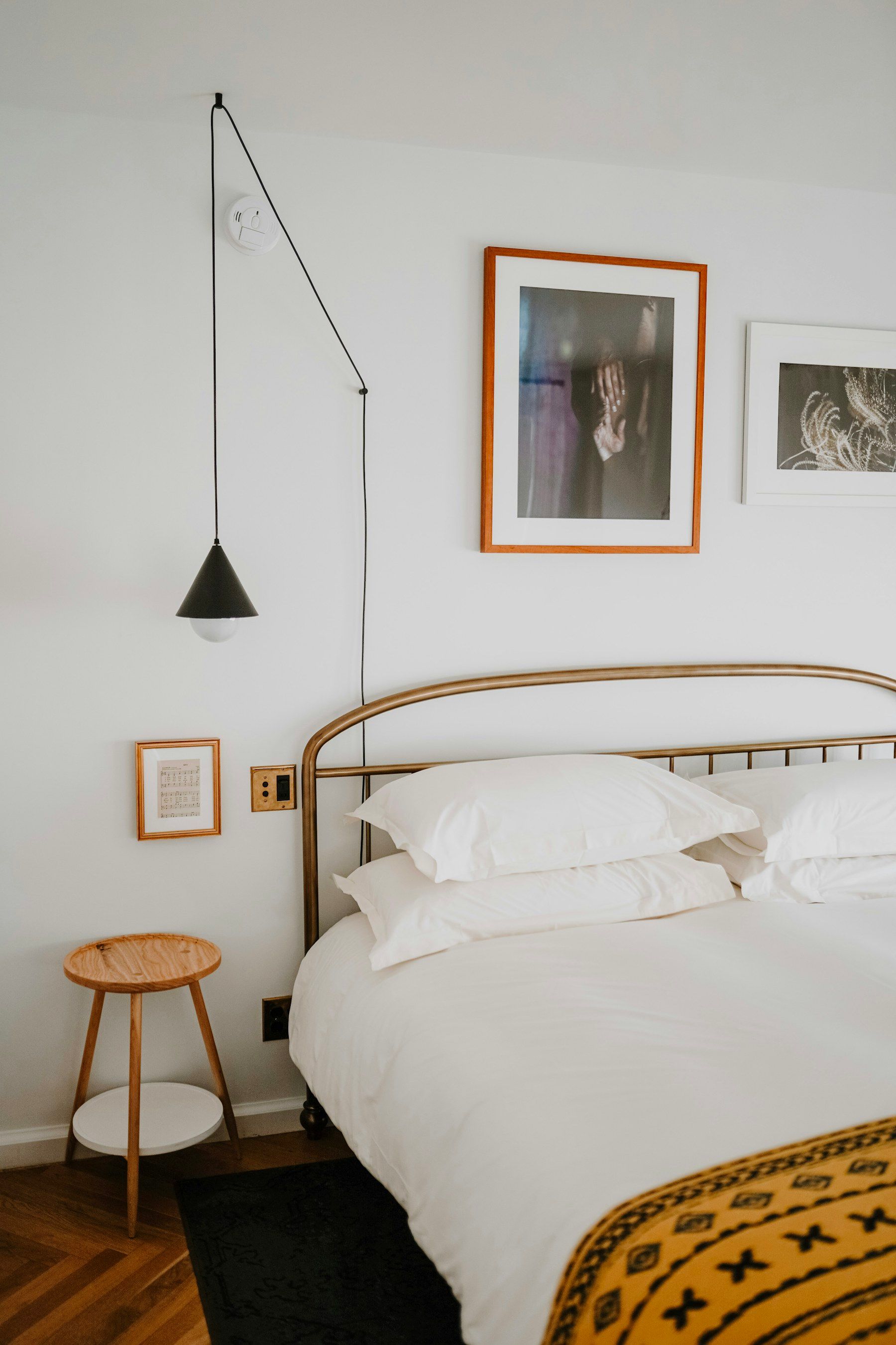 White bed with a mustard throw and framed prints