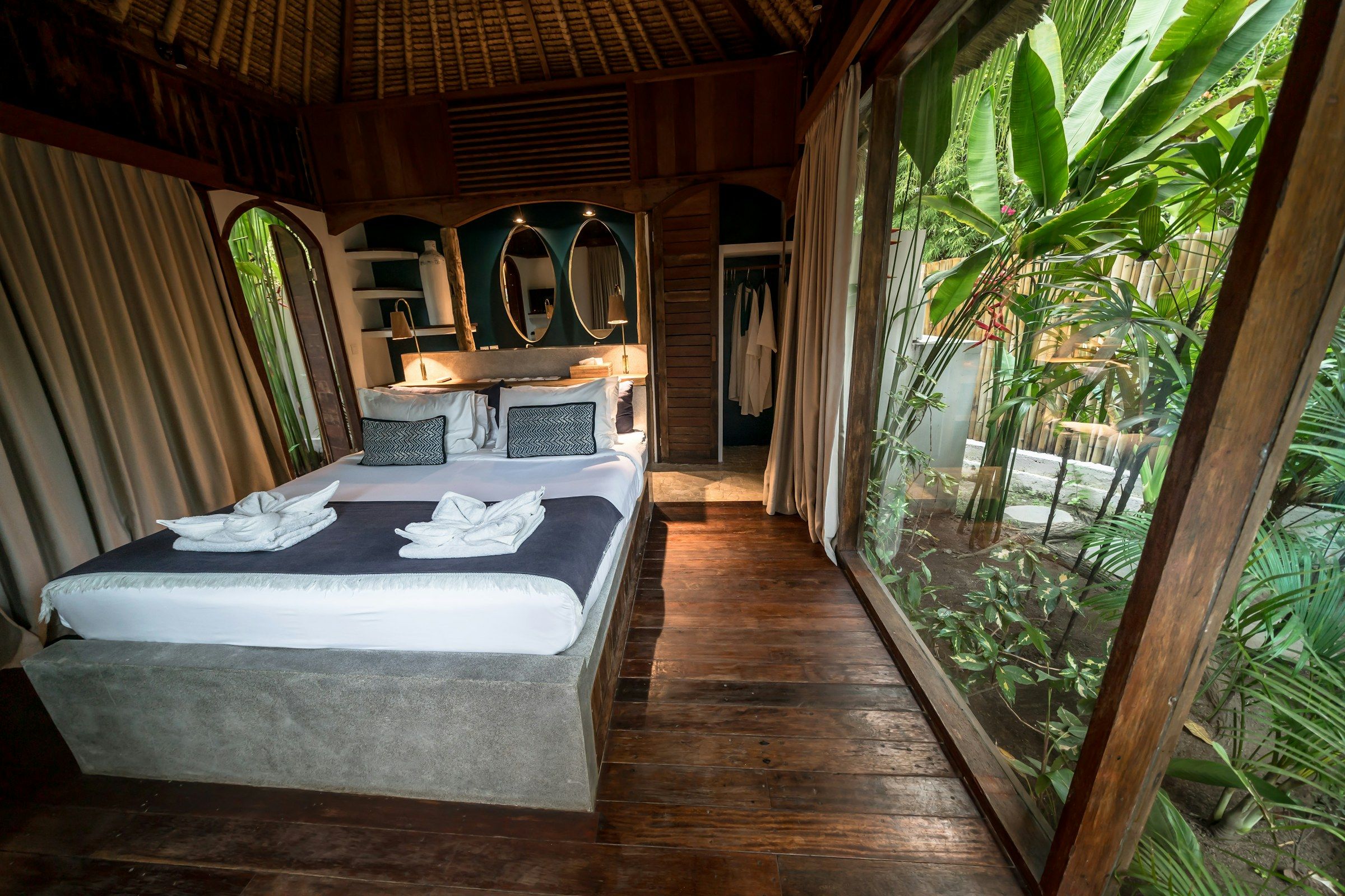 Bedroom with a wall of glass looking onto tropical plants